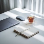 A clean, minimalist workspace with a cup of tea, a closed laptop, and a journal on the desk. The scene conveys tranquillity and focus, symbolising the sense of peace that comes from setting boundaries. There's soft lighting from a window, casting natural light across the desk, enhancing the serene mood.